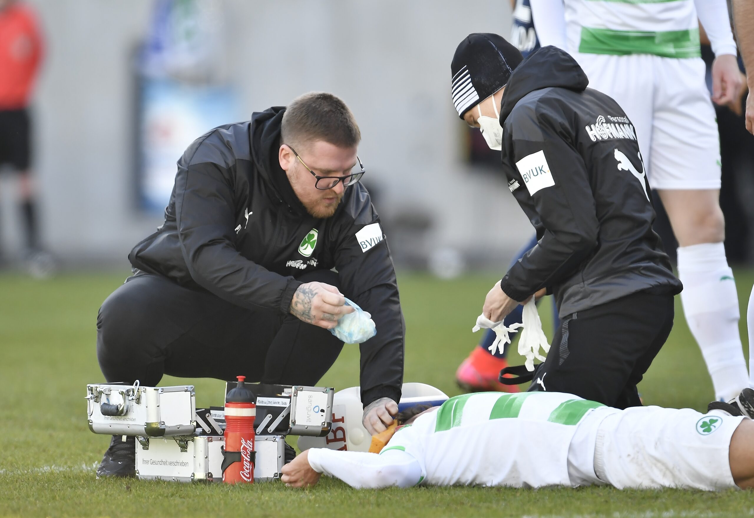 Physiotherapeut Patrick Rutte und sein Kollege behandeln einen Profisportler auf dem Fußballfeld