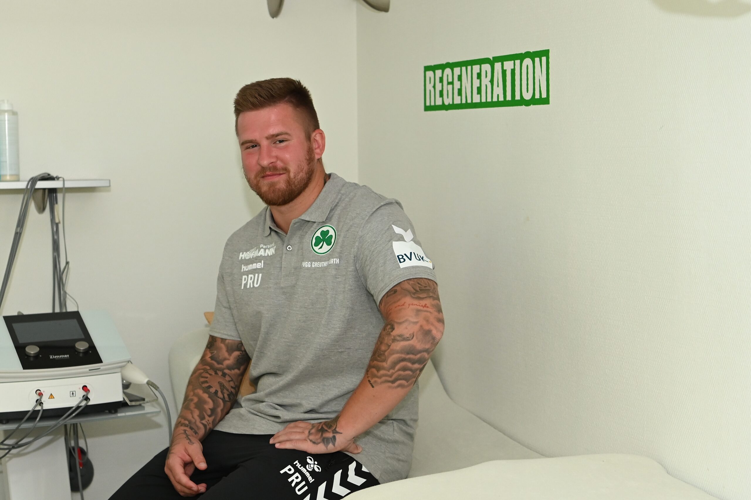 Physiotherapeut Patrick Rutte sitzt vor einem Schild mit der Aufschrift Rehabilitation